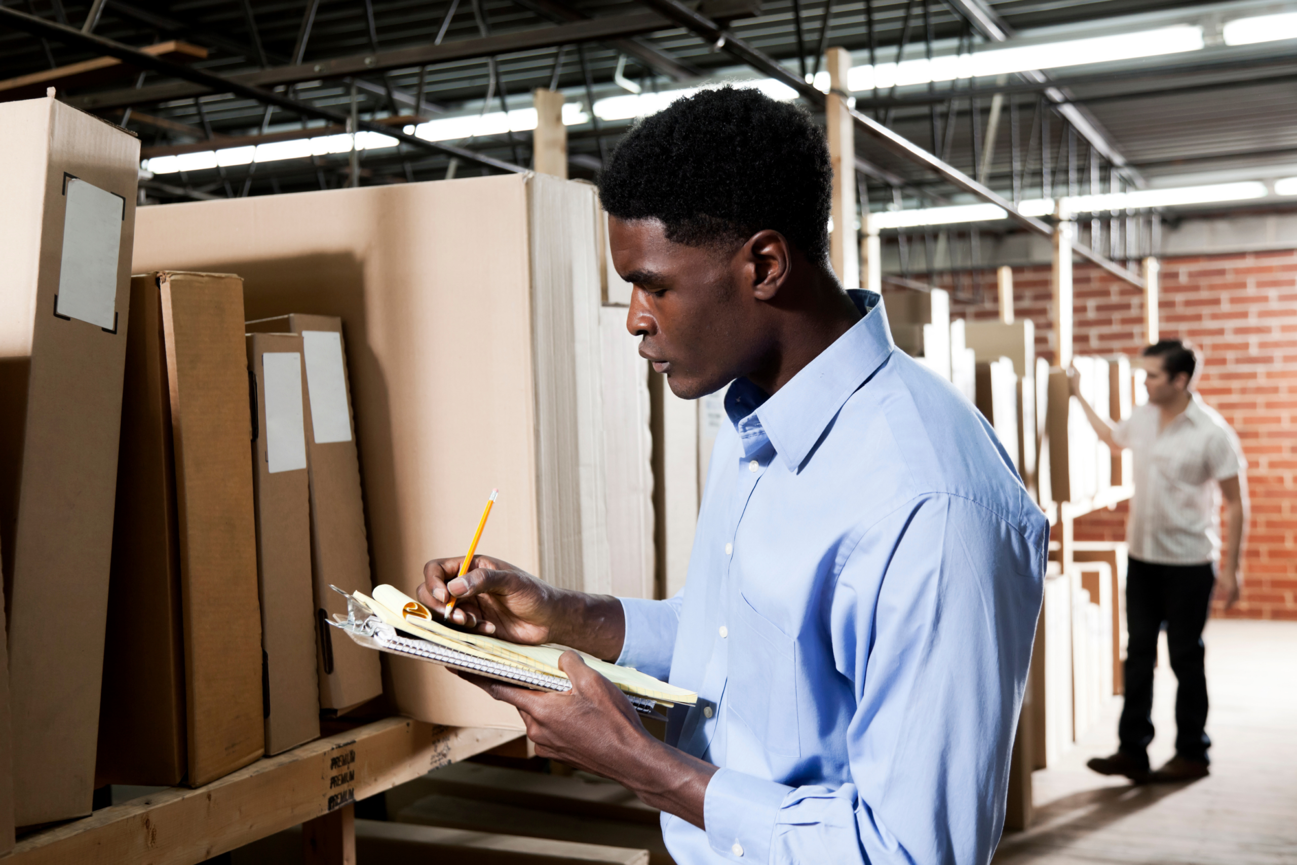 Decorative image of man writing notes in storage room.